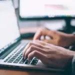 Person typing on a keyboard of a laptop.