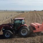 Tractor along a fence line in a dirt field