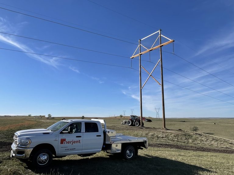 Merjent flatbed truck and tractor on electric transmission line right of way restoration project site.